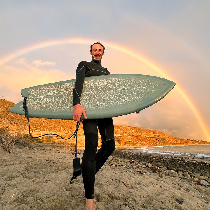 Surfer on beach with rainbow
