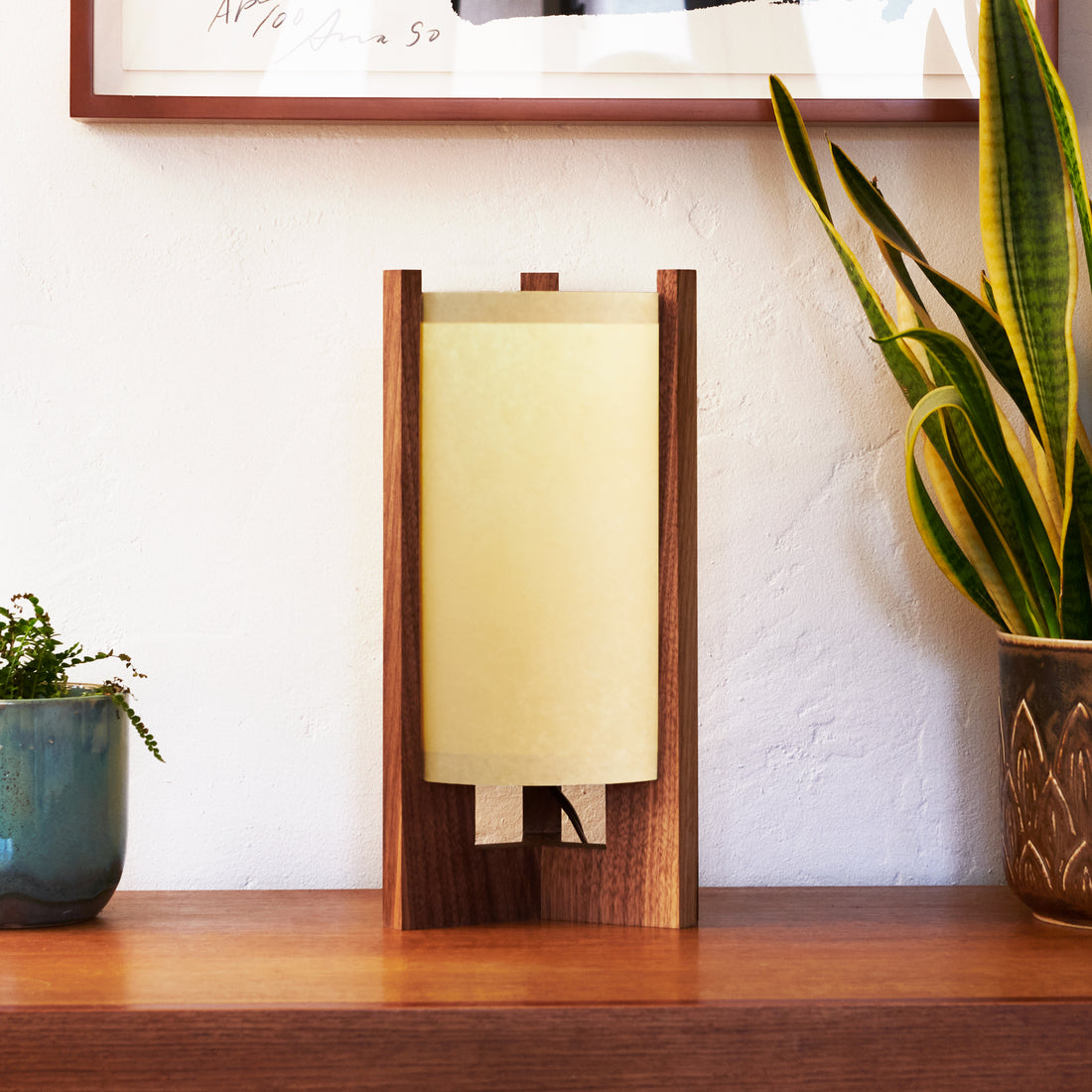 Walnut Table Lamp with Sand Lampshade on dresser next to plants and art