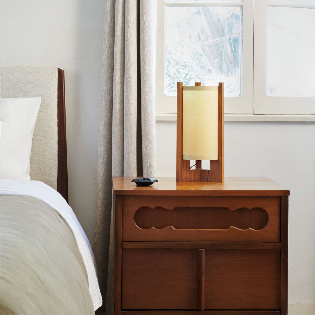 Teak Table Lamp with Sand Lampshade on nightstand next to bed and window