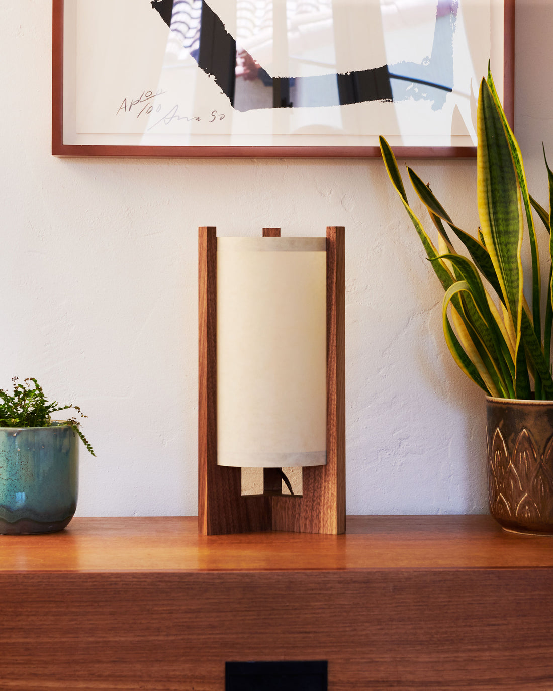 Walnut Table Lamp with Sand Lampshade on dresser next to plants and art