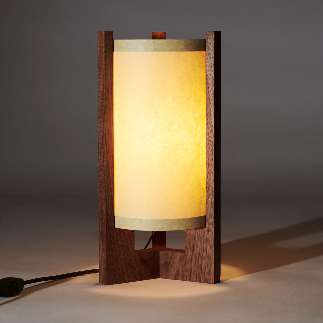 Japanese Mid Century Walnut Table Lamp that is illuminated